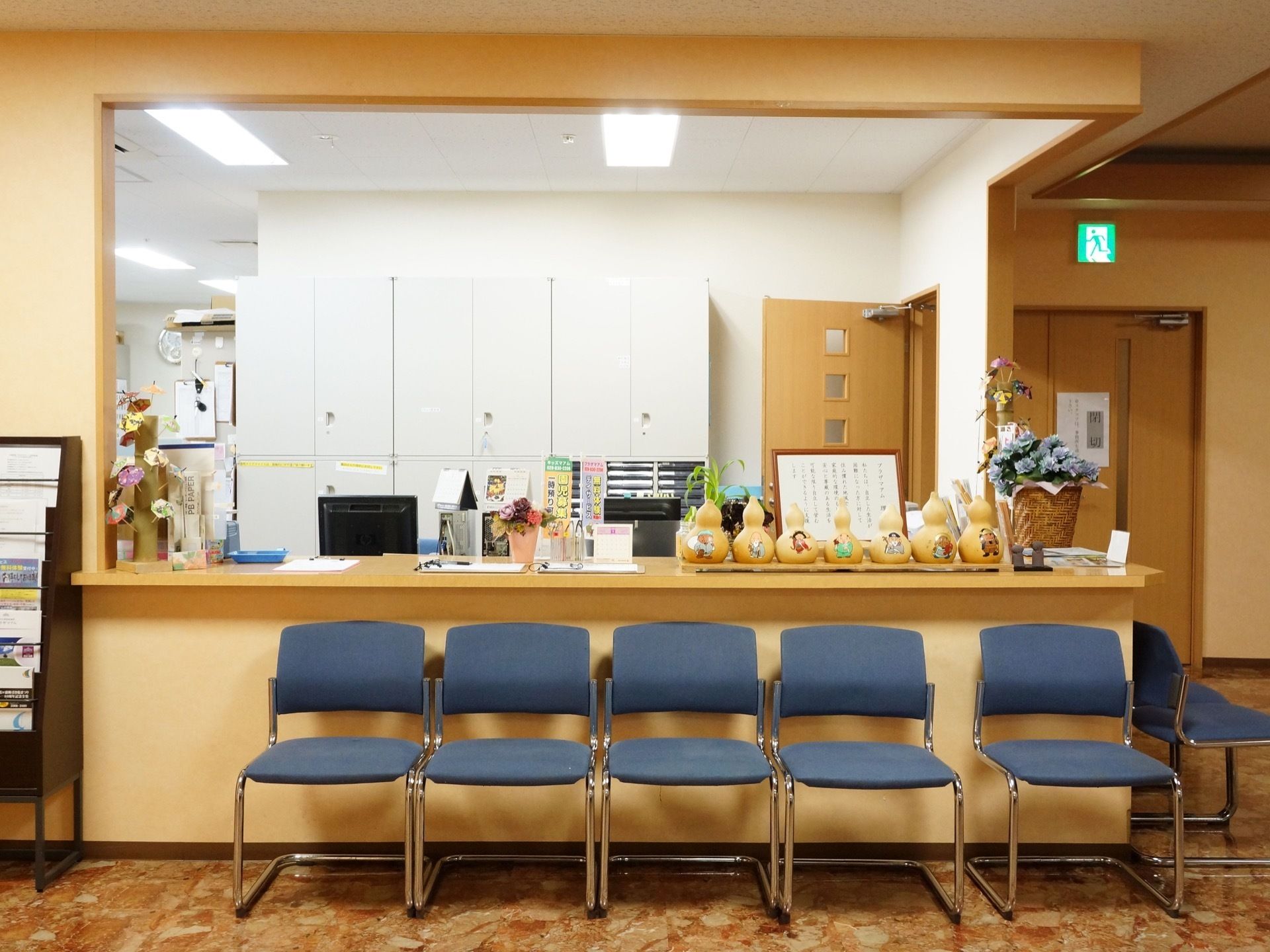 受付はクリーム色を基調としており、ここで対応してもらうことができる。すぐそばに青色の椅子が何脚も並べられている。