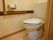 個室のお部屋についているトイレのため、そこまでの広さはない。便器と手すりが設置されている。木目調が基調となっている。