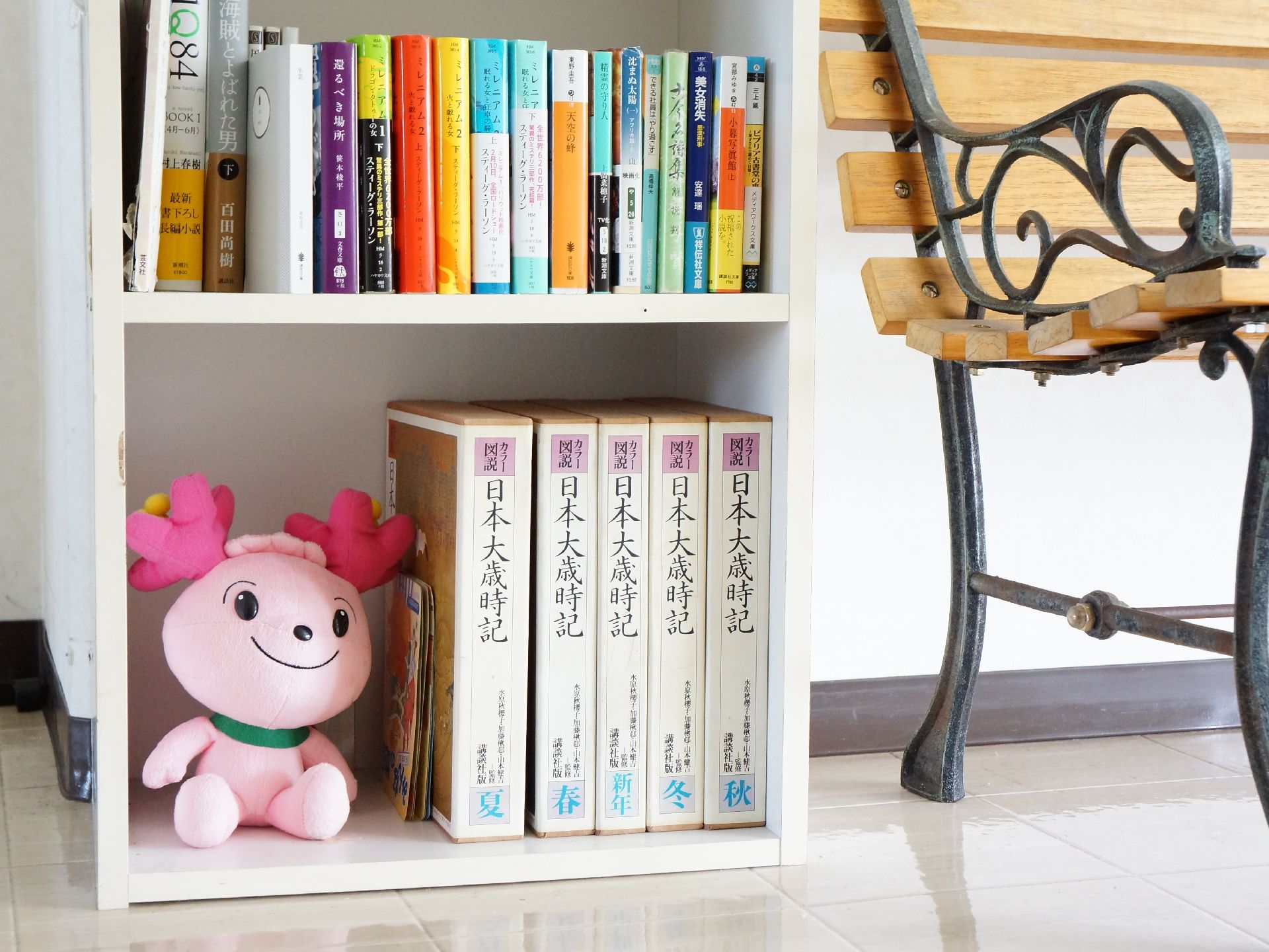 玄関ホールにはベンチの左側に白い棚が置かれている。内部には様々な種類の本が並んでいる。ぬいぐるみが飾られている。