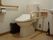 室内には安全のために手すりが設置されている。トイレ脇の壁に黒いイスが立てかけられ、トイレの横に手洗い場がある。