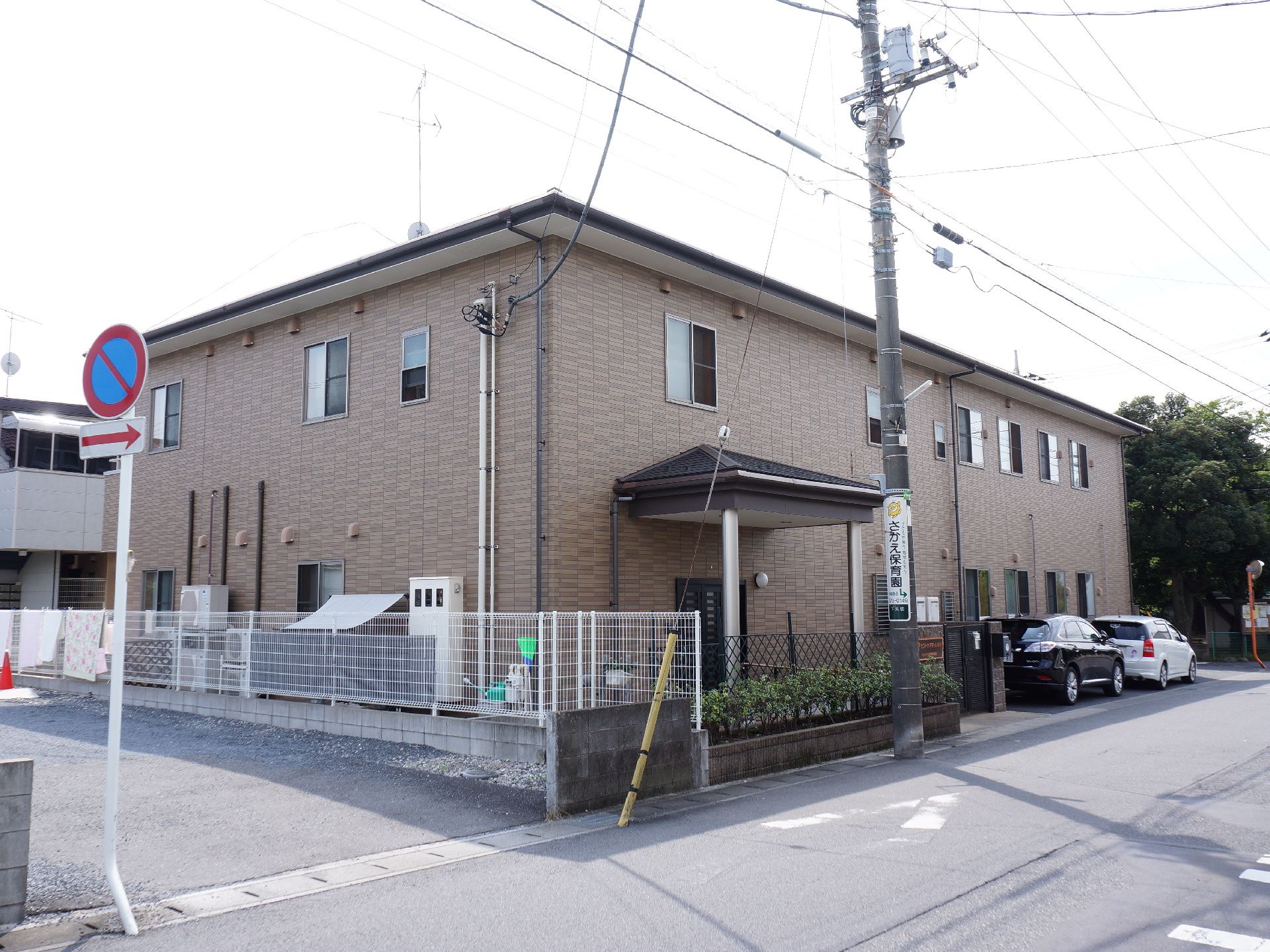 ブラウンの2階建てのシックな建物。外装は煉瓦造りのようにみえ、モダンでおしゃれな雰囲気。施設の前に2台車が停まっている。