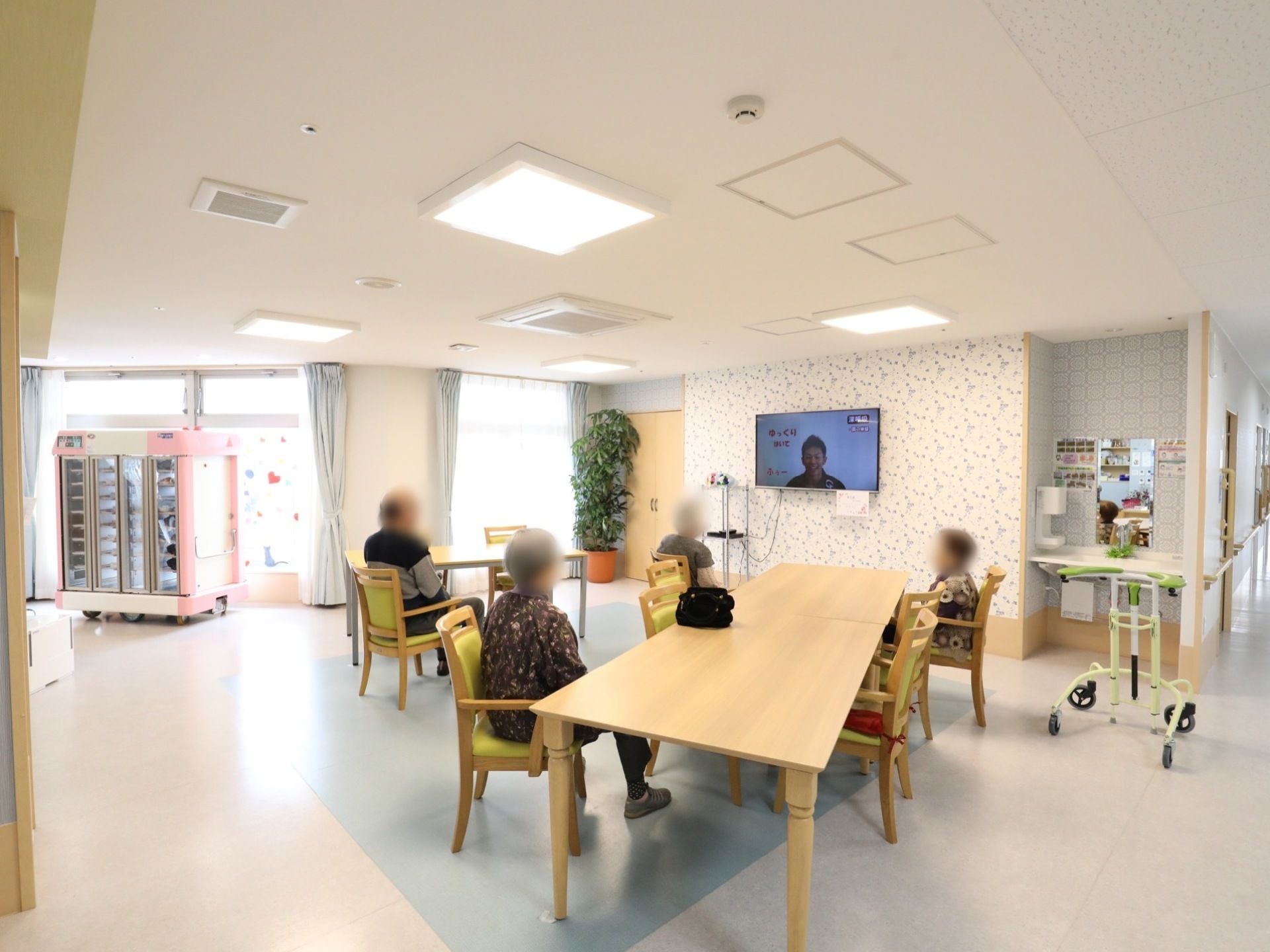 広々としたリビングルームで数名のご入居者様がテレビを観ている姿