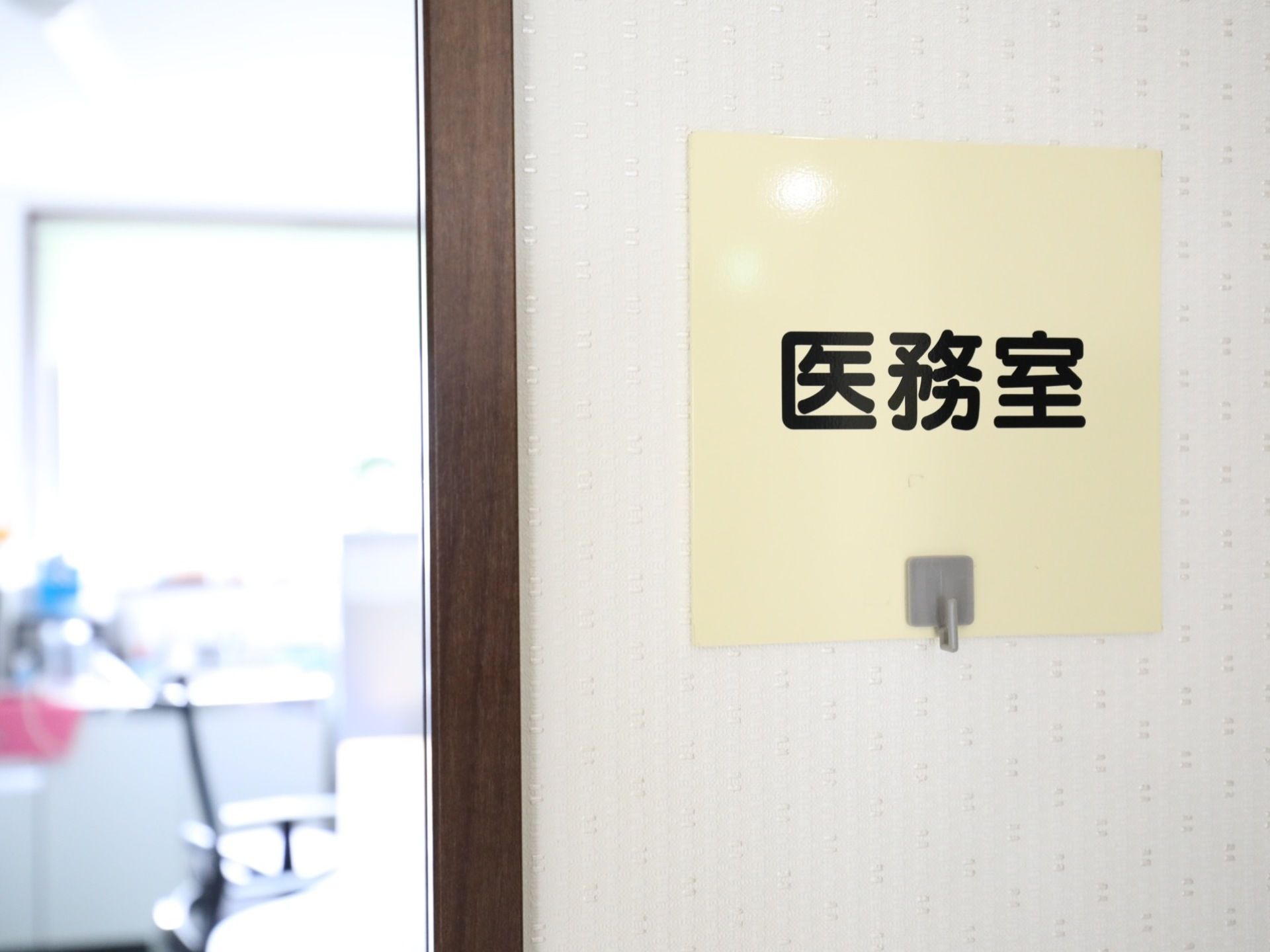 入口の壁に、フックの付いたサインプレートが貼られている医務室