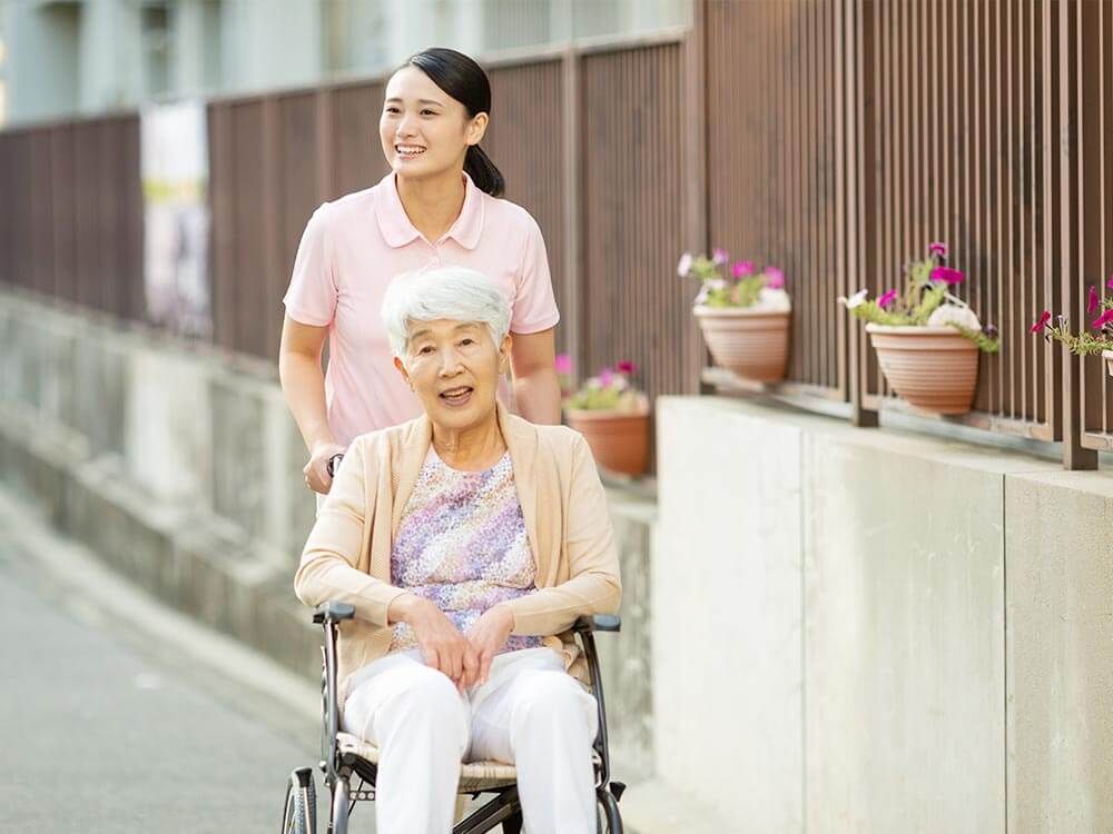 外出を楽しむ車椅子に乗った高齢女性と付き添いの女性ヘルパー
