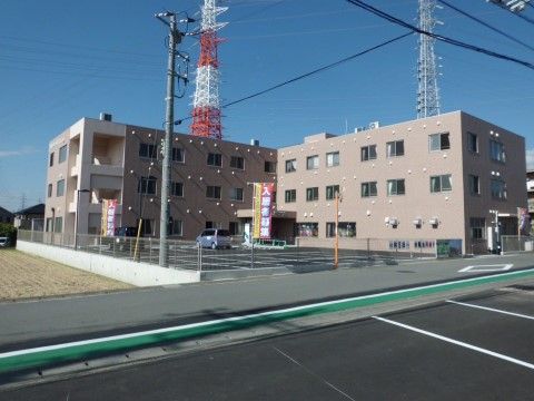 ベージュ色の落ち着いた建物の当施設は駐車場から建物内までバリアフリーで、入居者様には車から建物内まで車椅子でご移動いただける。