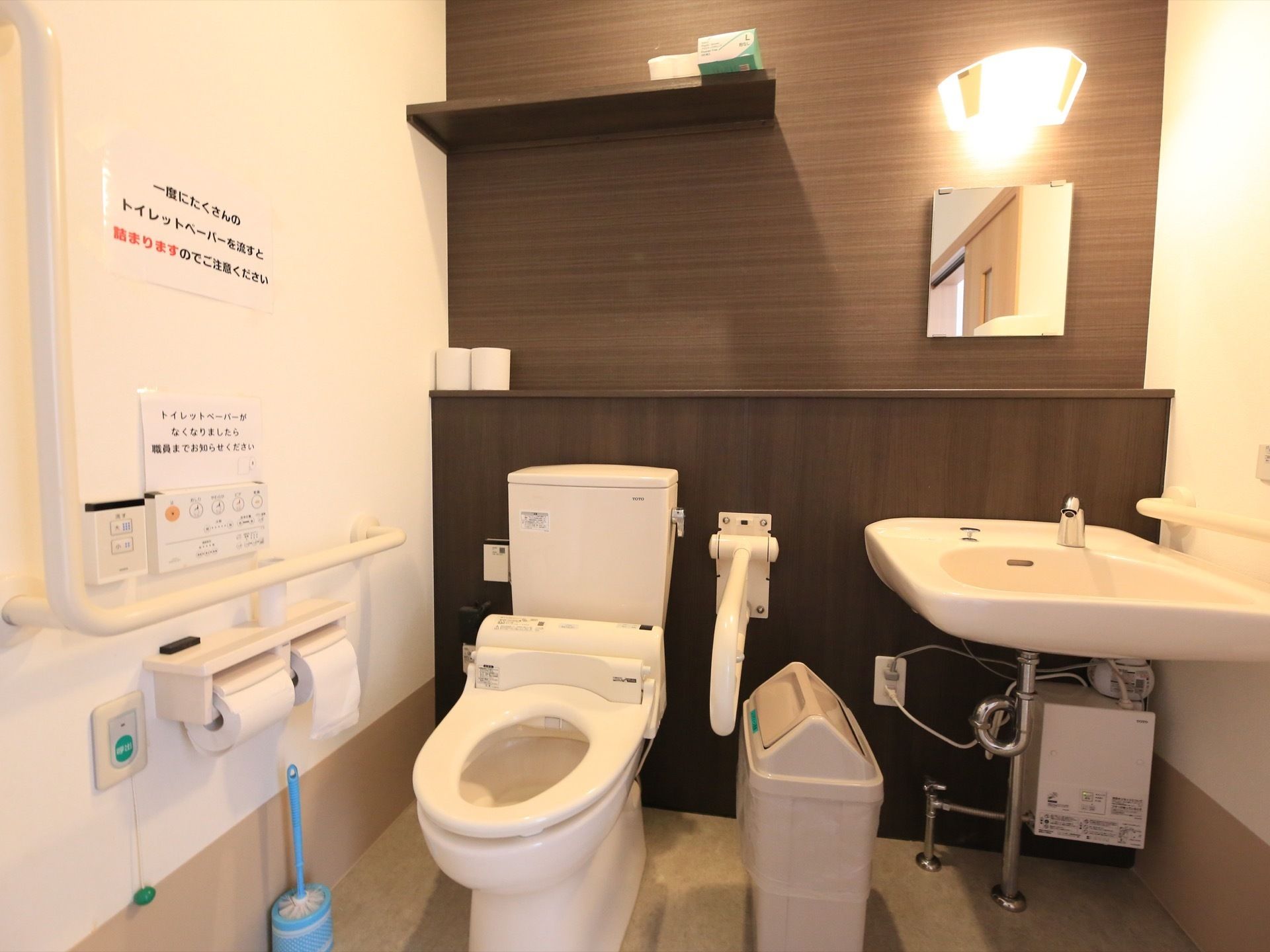 トイレは暖房洗浄機能つきの便座になっていて両側に手すりがついている。便座の横には、自動水栓がついた洗面台が設置されている。