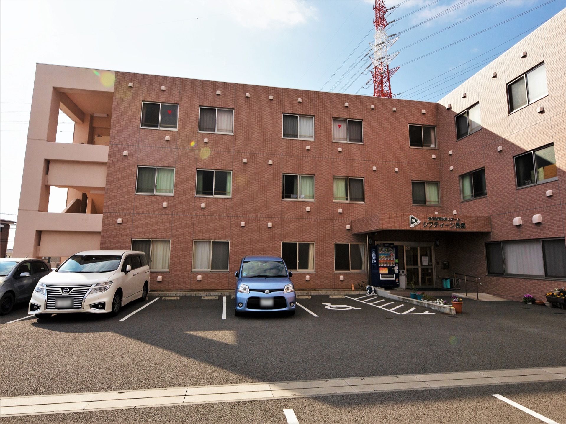 茶色を基調としたすっきりとした外観の施設である。玄関のすぐ横には、車椅子をご利用の方専用の駐車スペースがある。