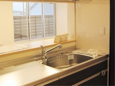 共用のキッチンには大きなシンクが設置され、キッチン台の下には収納スペースが設けられている。壁には窓があり、明るい雰囲気になっている。