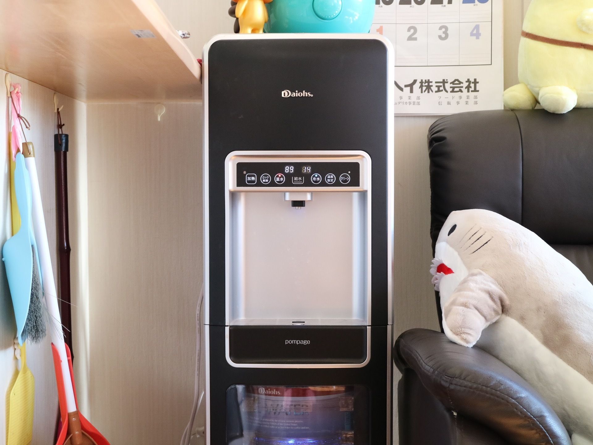 ソファーの横に黒を基調としたスタイリッシュなウォーターサーバーが１台設置されている。カウンター下には、掃除用具が用意されている。