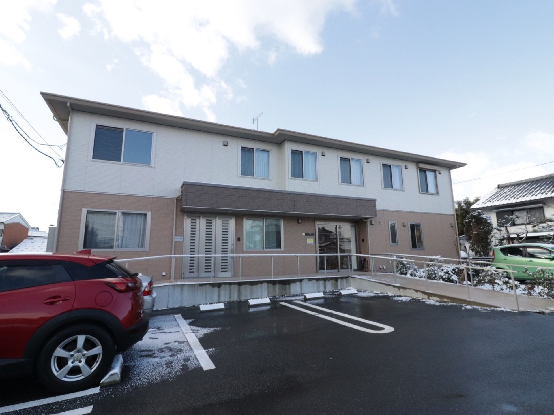 地上２階建て。１階の外壁は茶色で、２階は白になっている。玄関前にはスロープが設置されている。建物の近くに駐車場がある。