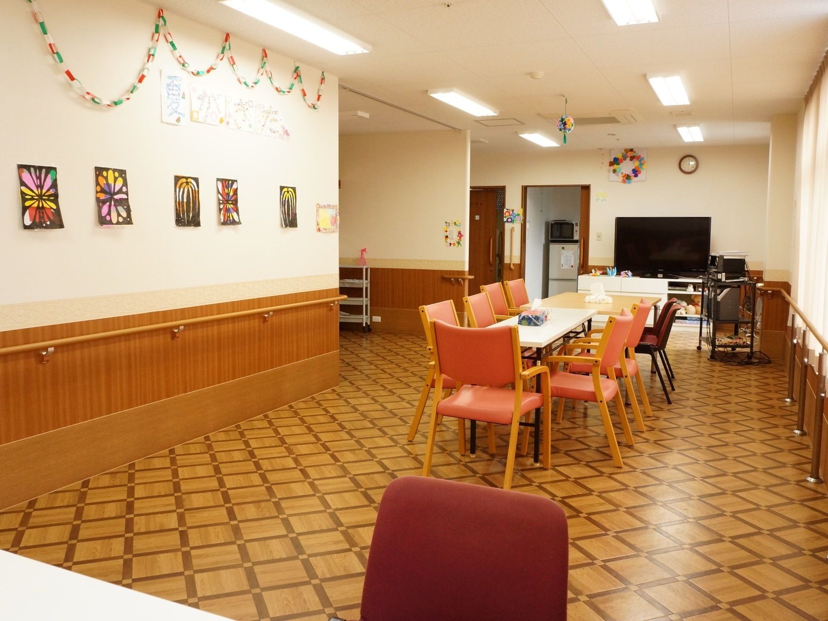 中央にはテーブルがあり、その上にはティシュが置かれている。左壁には紙の輪飾りが上側にあり、その下には沢山の絵が飾られている。