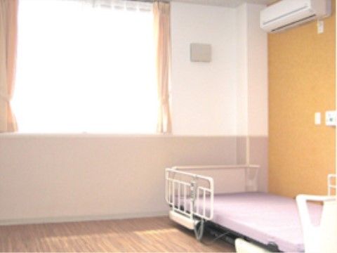 電動ベッドと空調機器があり、緊急コールボタンが壁に備わった居室