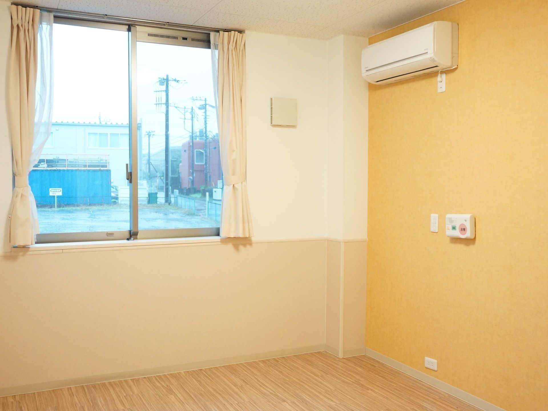 居室はフローリングになっている。大きな窓が付いている。壁にはエアコンやナースコールが設置されている。