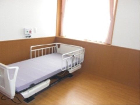 緊急コールボタンが壁に設置された、介護用ベッドのある居室