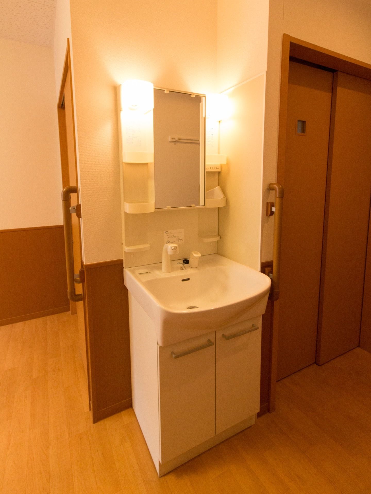 鏡の両側に照明が付いている。収納用の棚も左右に２段づつついているので、小物もすっきりと片付けられる。