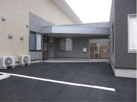 二棟の建物に挟まれるような位置に、ポーチ付きの玄関があるホーム