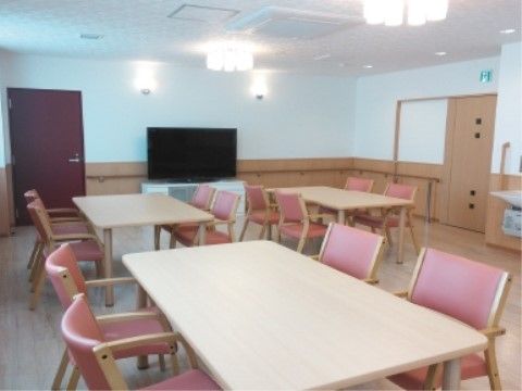 赤い肘掛椅子とテーブルが均一に並んだ、テレビのある食堂