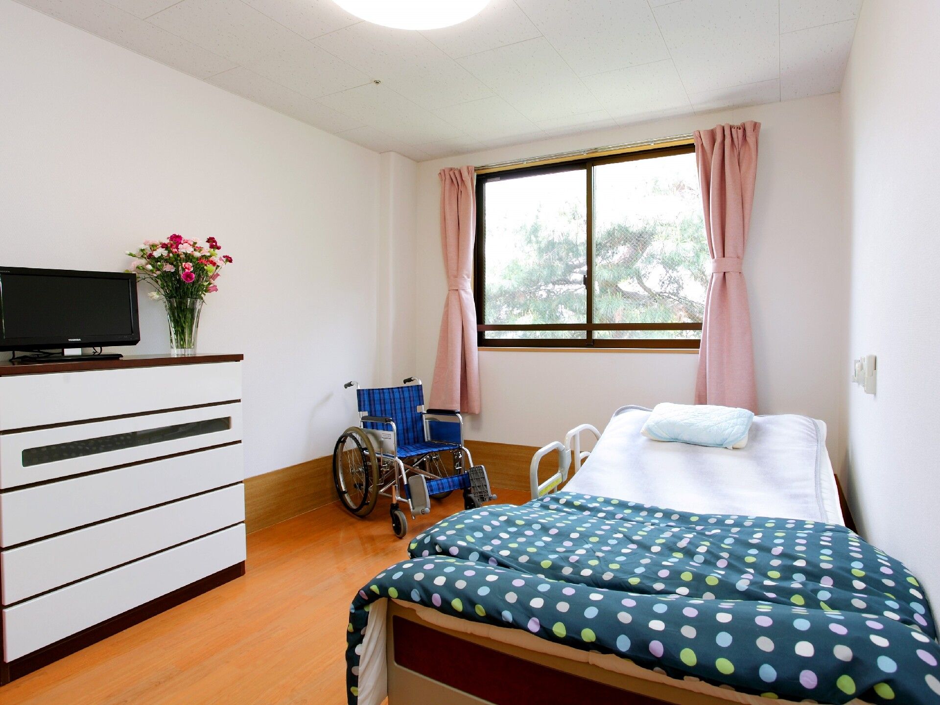 白い壁とフローリングの明るい雰囲気の居室。部屋の中央とトイレの前には、それぞれ照明が付いていて明るい。入り口のドアは間口が広い。