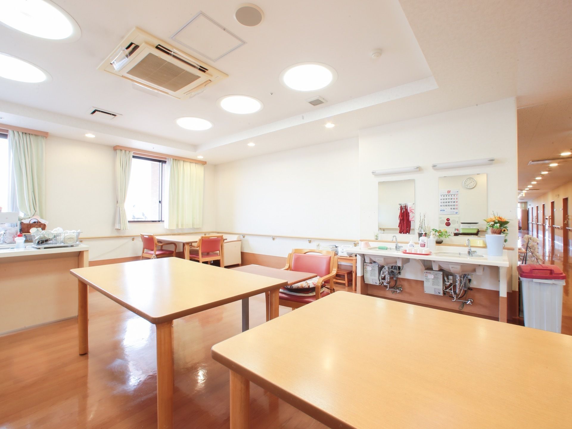 食堂には様々な大きさのテーブルと椅子が置かれている。洗面台は車椅子をご利用の方にもお使いいただけるよう、足元の空間を確保している。