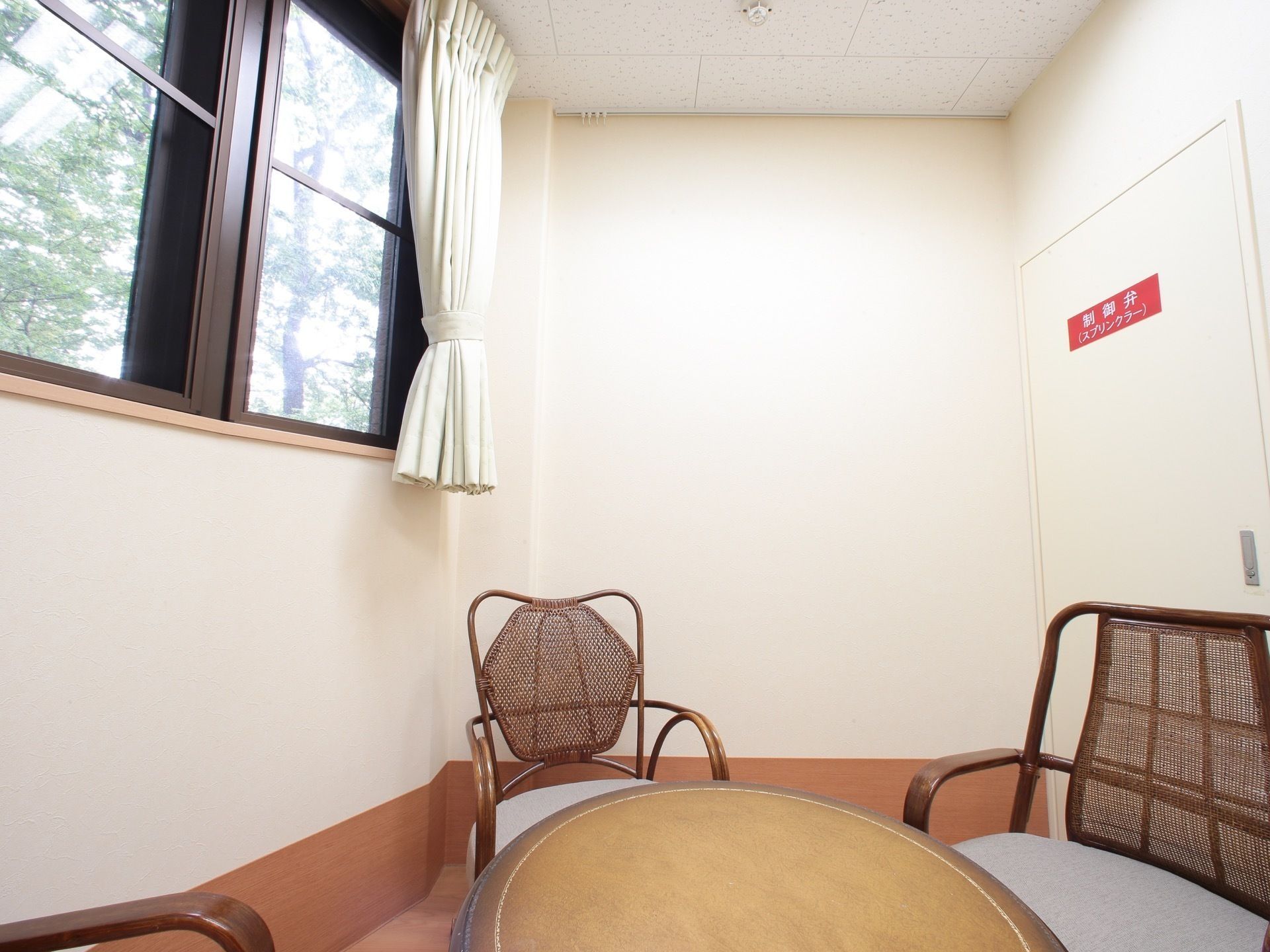 談話室の窓には厚めのカーテンが掛かっており、日照を調節できる。部屋の中央には、丸いテーブルと椅子が３脚設けられている。