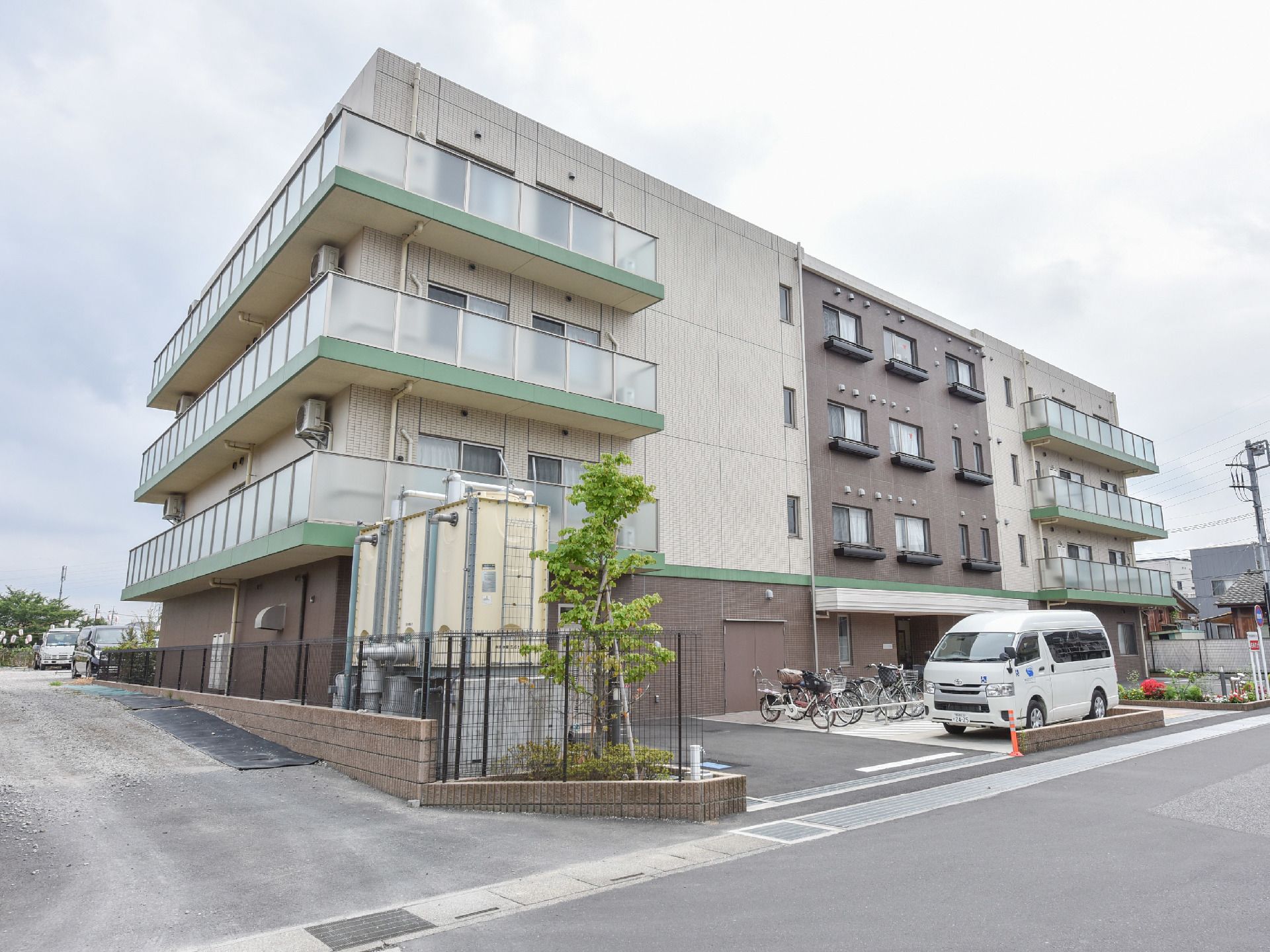 2階から上の住居部分には、バルコニーが設置されている。駐輪スペースや駐車場が建物前に設けられている。