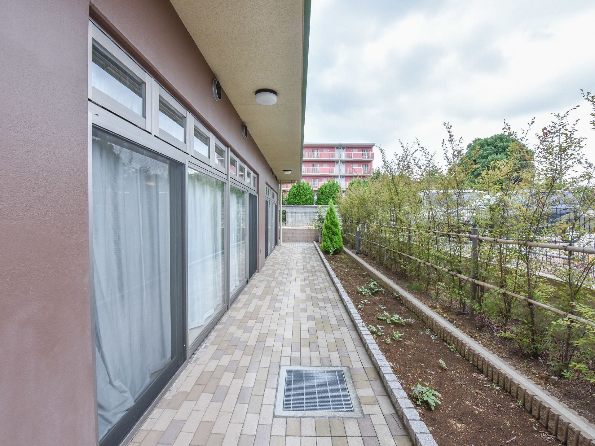 1階には、見通しの良い外廊下があり床にはタイルが敷かれている。フェンス沿って2段式の花壇が作られている。