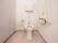 便座のすぐ横に、可動式の手すりが設置されている。トイレットペーパーホルダーが２つついている。その横に縦方向の大きな手すりがある。