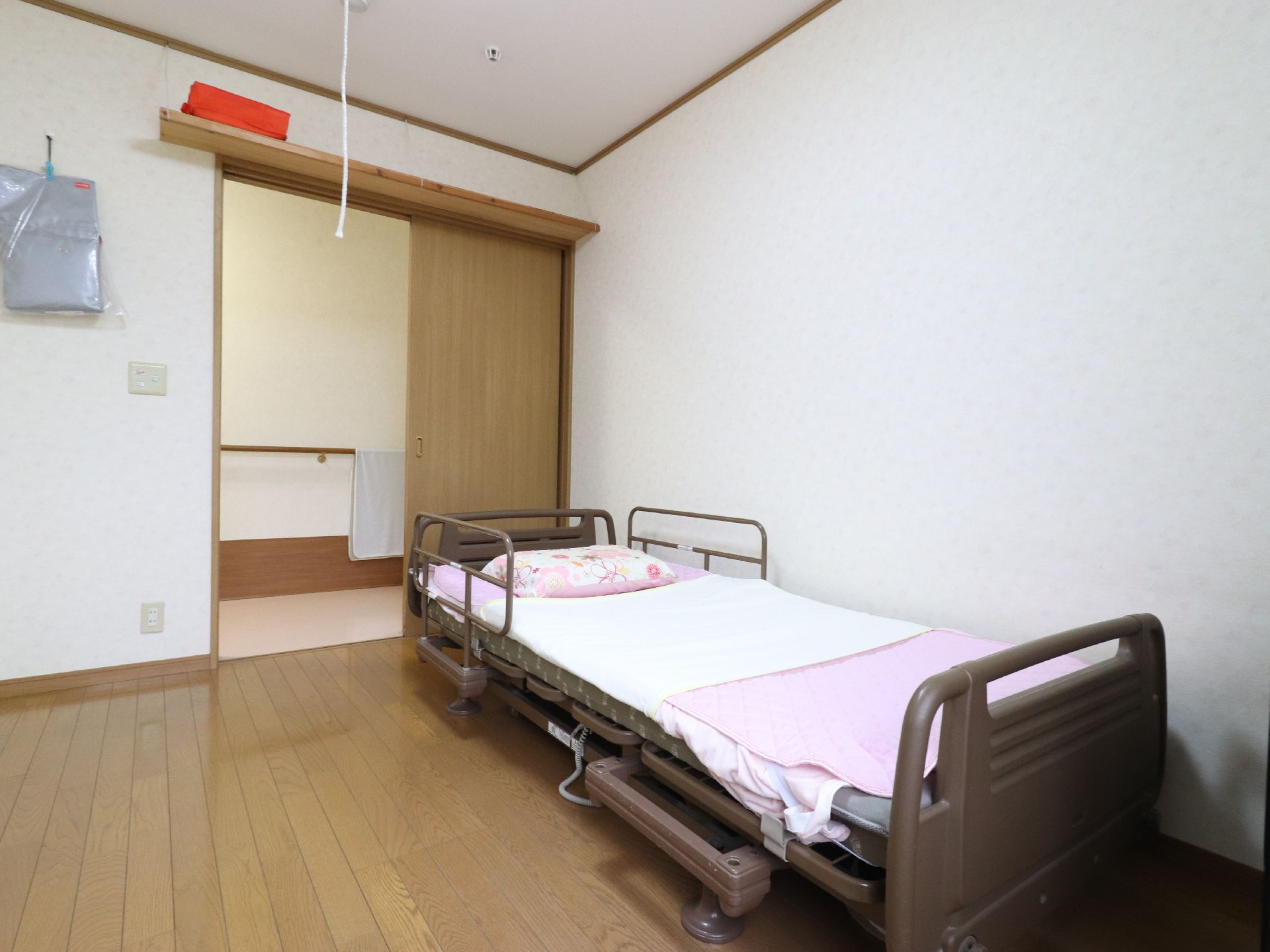 リクライニング機能がついた、介護用ベッドを設置している。また室内の入り口は開け閉めしやすい、スライド式のドアを採用している。