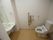 温水洗浄便座付きのトイレである。壁には手すり、アームレストが備え付けられている。洗面台が併設されている。