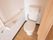 Ｌ字型手すりや呼び出しブザーが、設置されているトイレである。仕切りに薄いオレンジ色のカーテンが吊るされている。