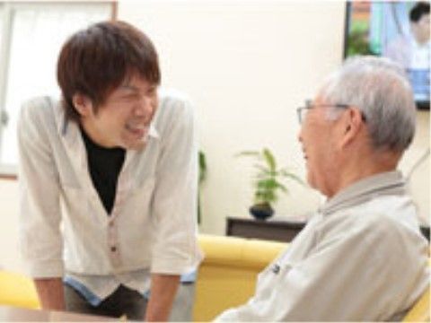 座っている入居者様に笑顔で話しかけている男性スタッフ