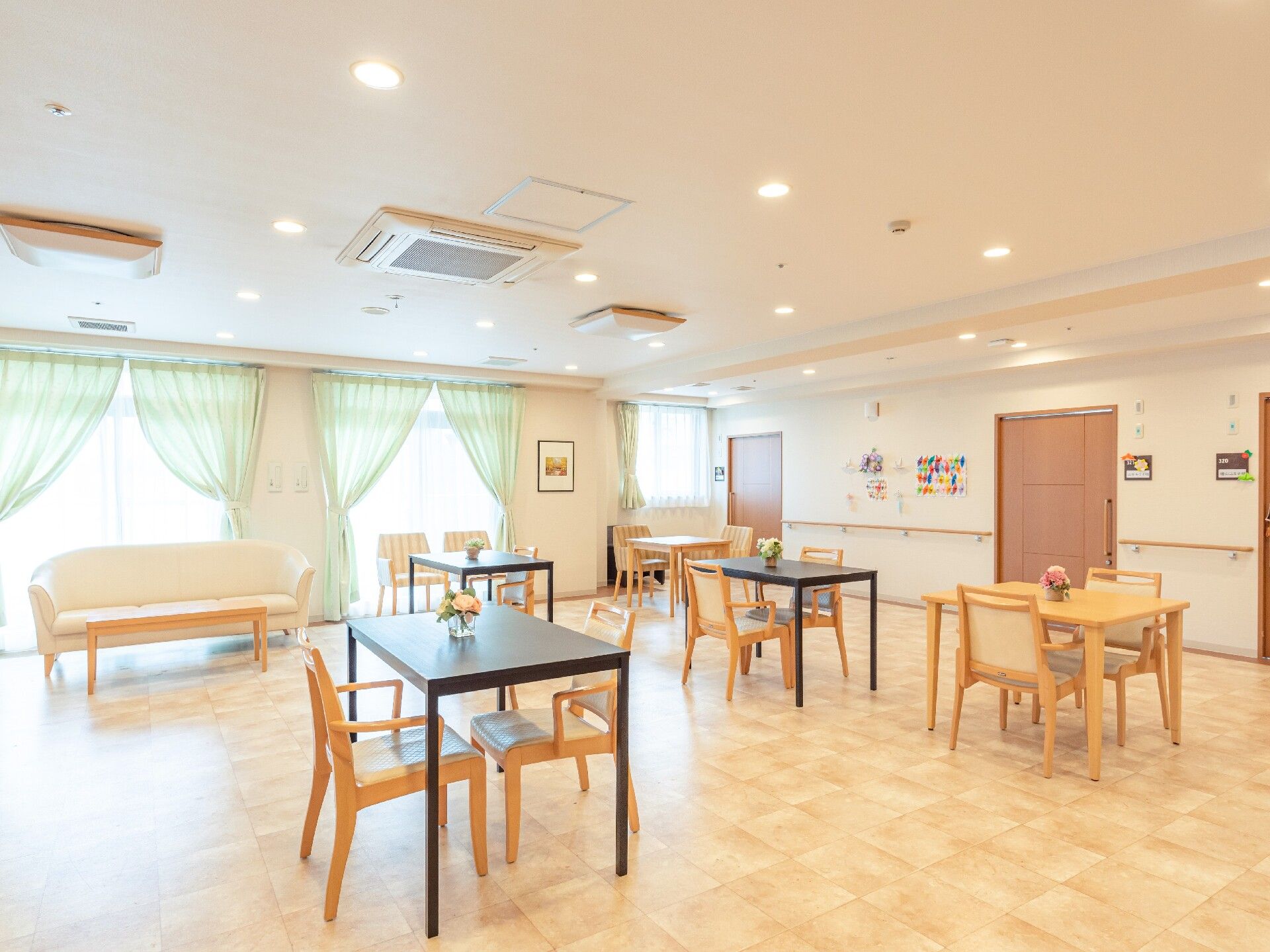木製のダイニングセットや木目調の床が温もりある空間となっている。棚や壁の装飾品がお洒落な食堂である。