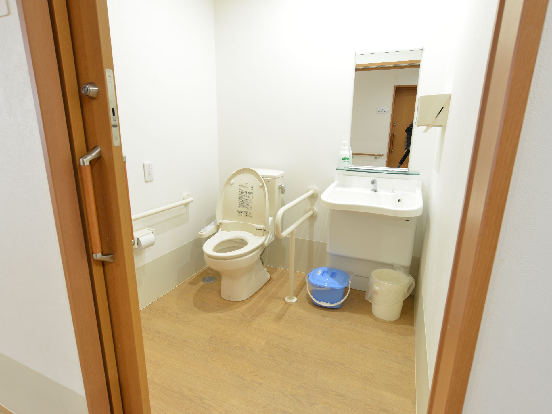 横引き式のドアを開けると、トイレ、手洗い場がある。便座には立ち上がる際にありがたい手すりを設置している。備品もきれいに整頓されている。
