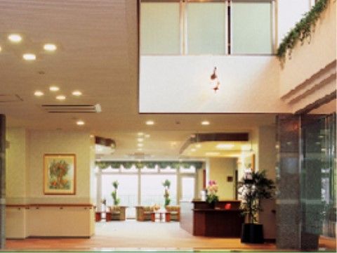 吹き抜けから差し込む光で明るいエントランス。観葉植物や木製のカウンターが設置されており、ホテルを思わせる雰囲気である。