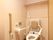 トイレの便座には背もたれがあり、脇には身体を支える肘置きが設置してある。壁には操作パネルがついている。