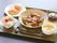 豚カツにご飯、サラダ、お味噌汁、お漬物、デザートのバナナがそれぞれきれいにお皿に盛りつけられている。お箸とフォークが付いている。