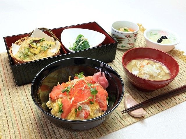 ランチョンマットの上に置かれている海鮮丼や天ぷら、茶碗蒸しなどの食事