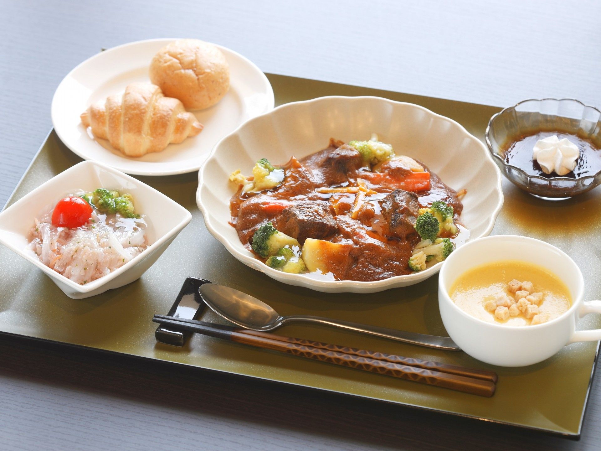 ある日のお魚メインの食事メニュー。食事は一人分ずつお盆にお皿が並べられている。食後のフルーツも添えられている。
