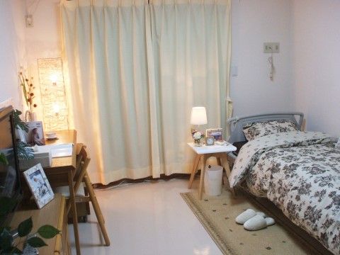 右の壁際にベッドがあり、その枕側の壁にナースコールが備わっている。机や椅子、チェスト、サイドテーブルなどの家具も置かれている。