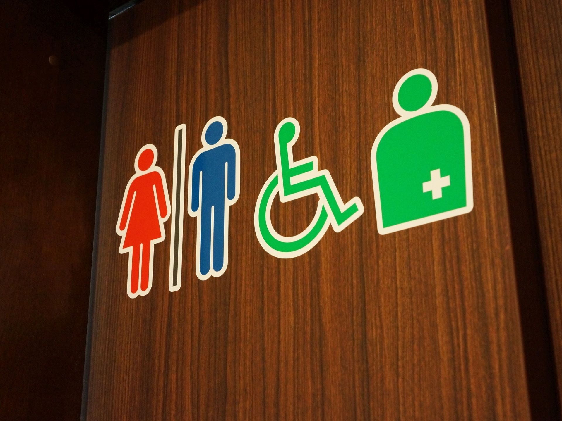 多機能型トイレの扉には、男女対応、車椅子対応、オストメイト対応の3種類のマークが大きく表示されている。