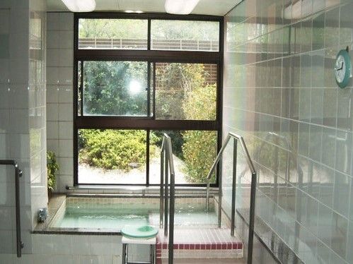 青みがかったタイルの浴室であり、奥には開け閉めが可能な大きな窓が置かれている。窓からは庭の緑を楽しむことができる。
