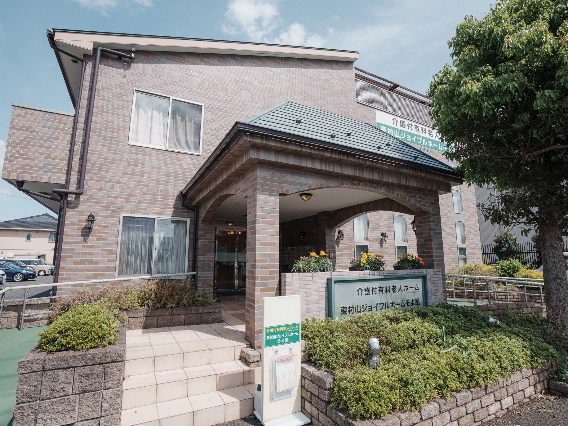 「東村山ジョイフルホームそよ風」の外観。建物周辺に緑を配している。