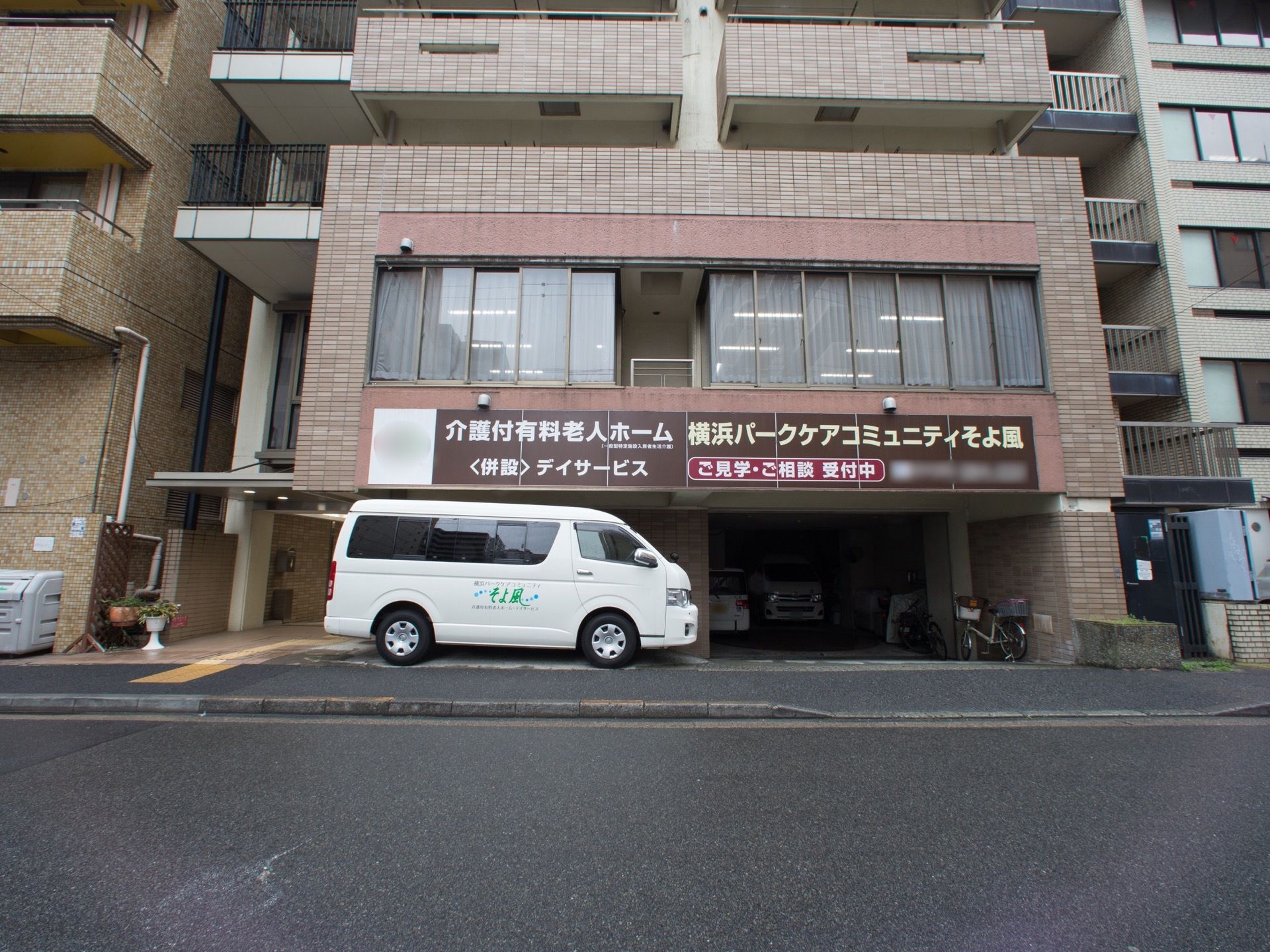 茶褐色のタイル張りの、マンションのような外観。１階は駐車場とエントランスになっていて、雨でも濡れずに出入りが可能になっている。