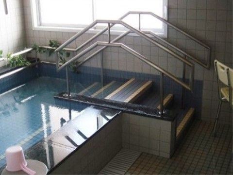 タイル張りの浴室に、複数のご入居者が同時に入浴できる浴槽がある。浴槽の出入り口には、段差が低めの階段が設置されている。