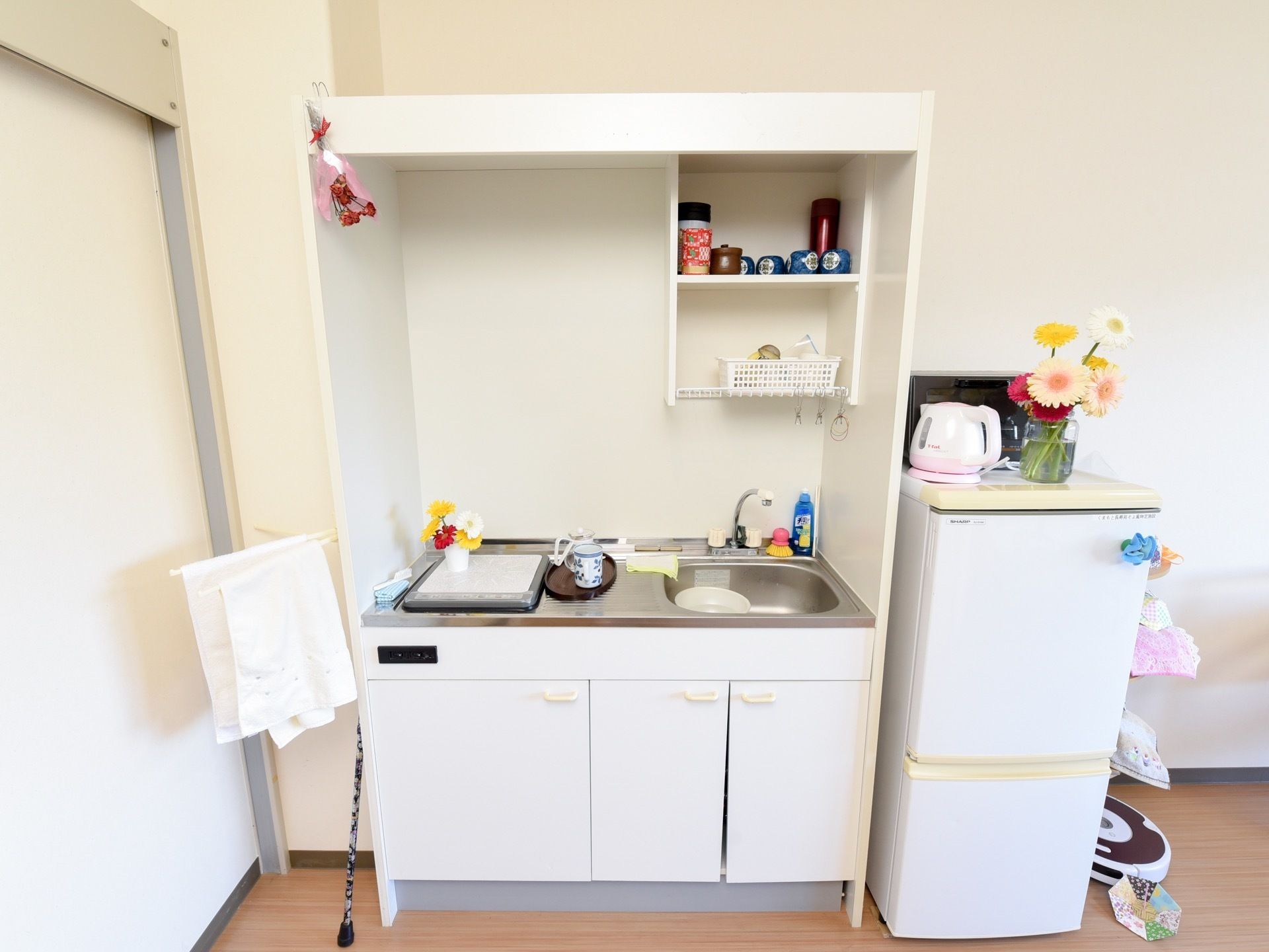 居室の一角には簡単な調理ができるキッチンが整えられている。コンロは電化式であり、食器を並べることのできる棚や収納スペースも付属している。