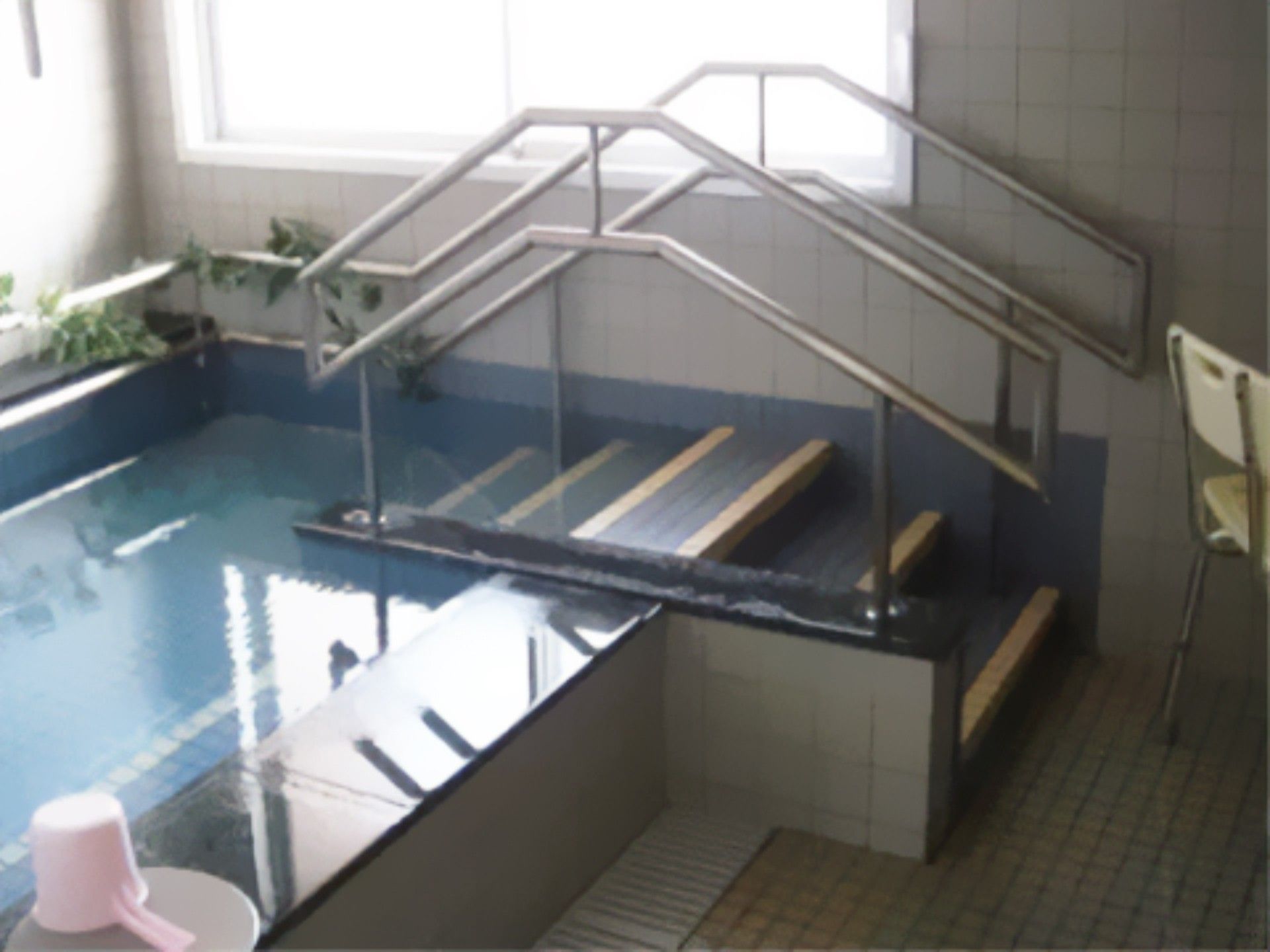 タイル張りの浴室に、複数のご入居者が同時に入浴できる浴槽がある。浴槽の出入り口には、段差が低めの階段が設置されている。