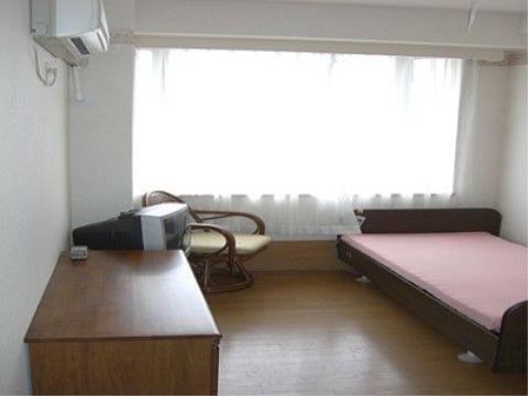 広いベッドや落ち着いた色調の調度、大きな窓が特徴の居室の一例