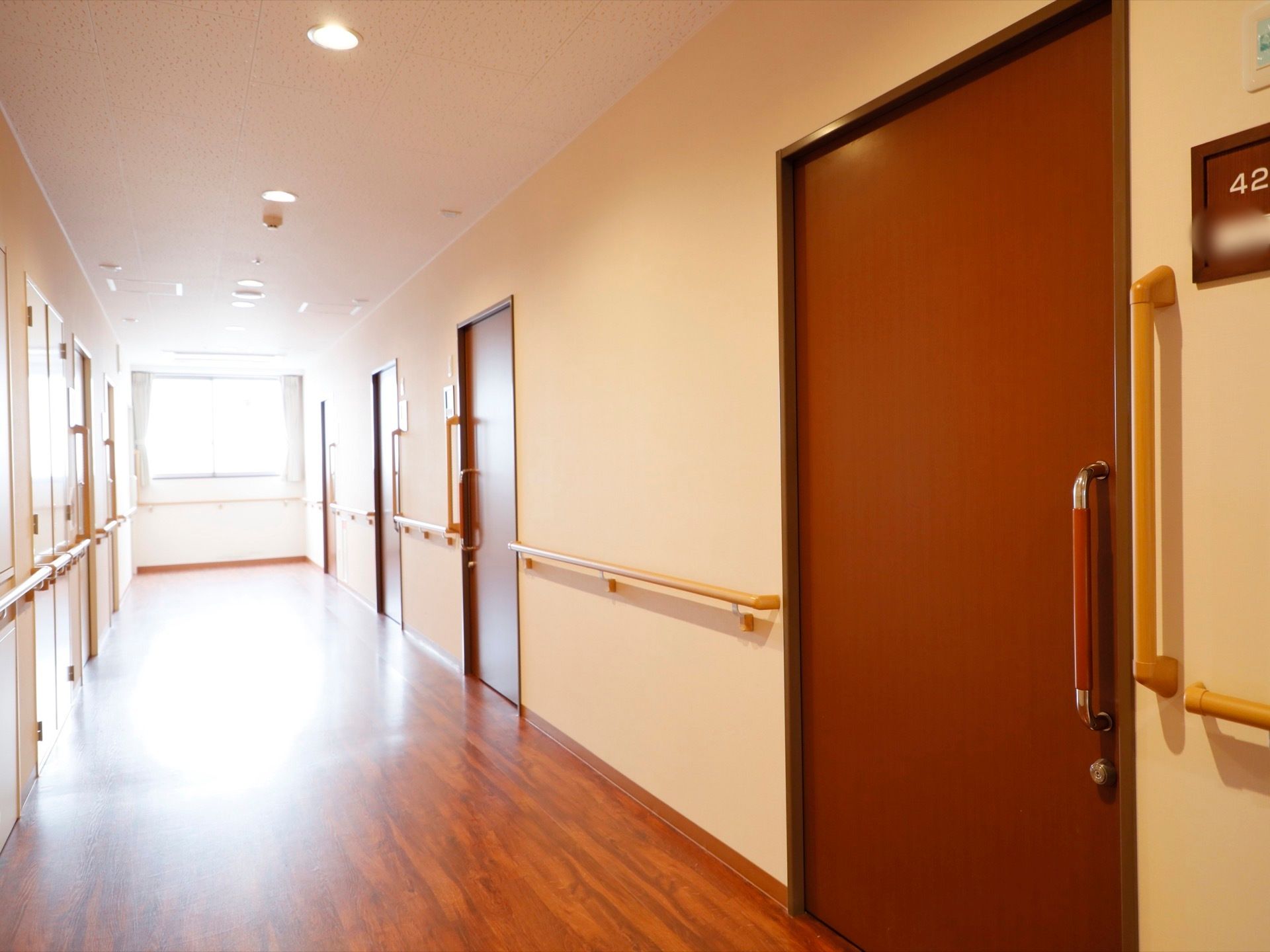 広くまっすぐな通路のつきあたりに窓がある。通路の両側に手すりがあり、居室入り口は横開きのドアがついている。