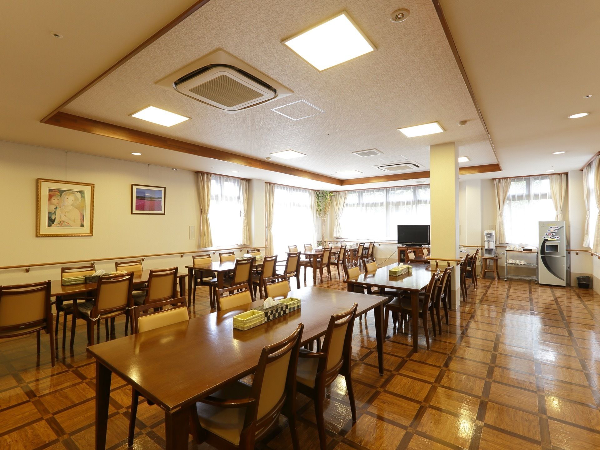 多くの入居者様らが集まって食事を取るための食堂。木製の各テーブルの上にはボックスティッシュが常備されている。