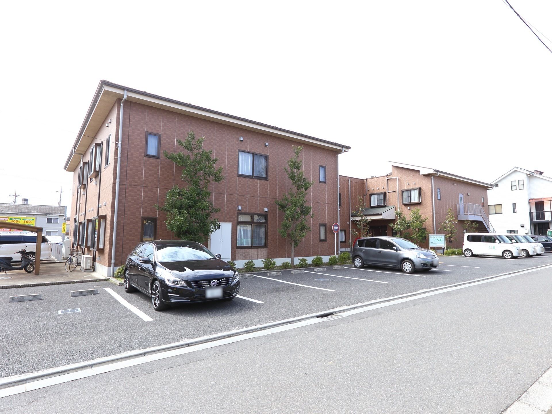 鉄筋コンクリート造りの２階建ての施設外観。建物外壁にはレンガ風の化粧パネルが貼られ、手前には駐車場がある。